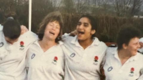Four women stood shoulder to shoulder wearing England Rugby shirts
