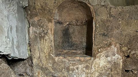 A wall with a section cut out for a place to hold statues of household gods