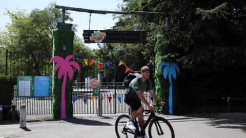 The closed gates of the theme park with a staff member in front