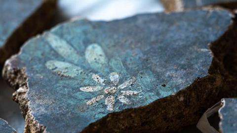 A piece of blue mural with a painting of a white flower on it.