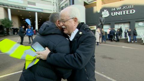 John hugging a football fan outside Newcastle United's stadium