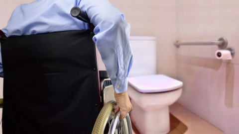 Wheelchair user in adapted home bathroom