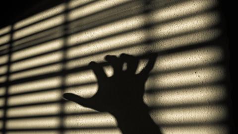 A shadowed hand on the blinds