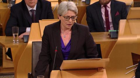 Scottish Conservative MSP Annie Wells tells Holyrood that coming to terms with being gay as a young teenager took her to a "dark and confusing place".