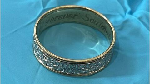 Engraved ring on blue cloth. The words "forever soulmate" are visible on the inside of the ring