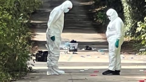 Crime scene investigators looking at the ground in Distillery Lane, Colchester