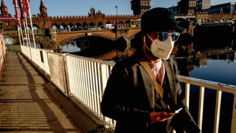 A man wears mask as walks next to Oberbaum Bridge in Berlin, Germany, 2 March 2021