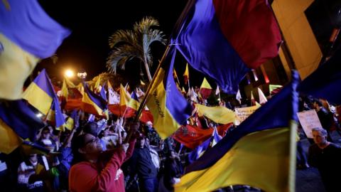 Costa Ricans waving flags and supporting their candidates outside a presidential debate