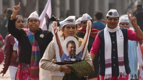 A woman carries a cutout of Delhi Chief Minister Arvind Kejriwal during a road show before filing his nomination for the upcoming assembly election, at Connaught Place on January 20, 2020 in New Delhi, India.