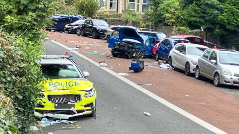 A police car smashed up and several others damaged too on a road