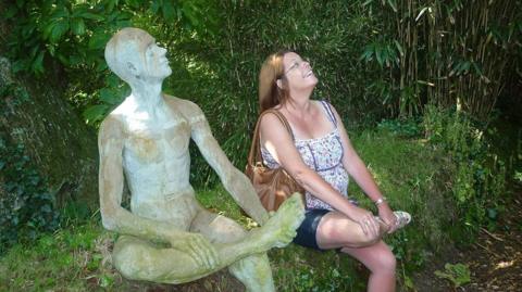 Woman sitting with a sculpture of a figure