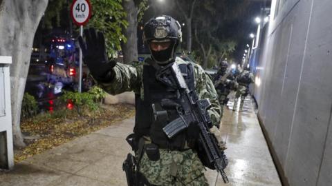 A soldier gestures as military forces guard the headquarters of the Specialized Prosecutor's Office for Organized Crime (Femdo) following the transfer of Nestor Isidro Garcia 'El Nini', alleged head of security of Los Chapitos criminal group, in Mexico City, Mexico, 22 November 2023.