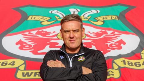 Andy Lowe in front of a Wrexham crest