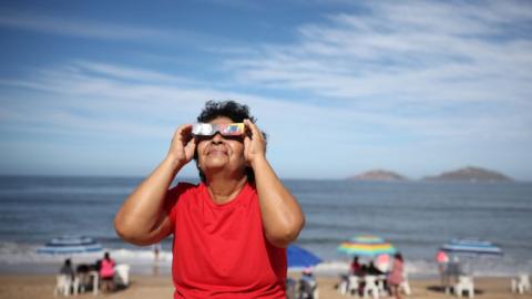 A woman puts on her glasses to see the eclipse on April 08, 2024 in Mazatlan, Mexico