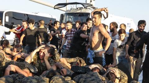 An unidentified man uses his belt to hit Turkish soldiers involved in the coup attempt that surrendered on Bosphorus bridge on Saturday in Istanbul, Turkey