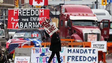 A protester walks in front of parked trucks as demonstrators continue to protest the vaccine mandates implemented by Prime Minister Justin Trudeau on February 8, 2022 in Ottawa