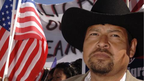 Juan Galvan holds a U.S. flag as he participates in the Mega March on City Hall April 9, 2006 in Dallas, Texas