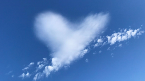 Clear blue skies with a love heart shaped cloud in the centre of the image