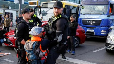 Police officers carry away a climate activist who is part of a group blocking the street during morning rush hour in Berlin, Germany October 31, 2022