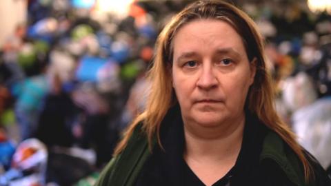 Organiser Magda looks at the camera, with bags of donated goods visible in the background.