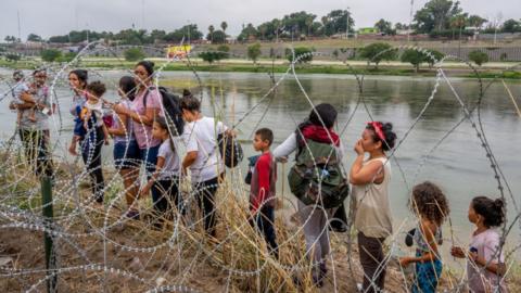 People seeking asylum speak with law enforcement after illegally crossing the Rio Grande into the United States on June 14, 2023 in Eagle Pass, Texas.