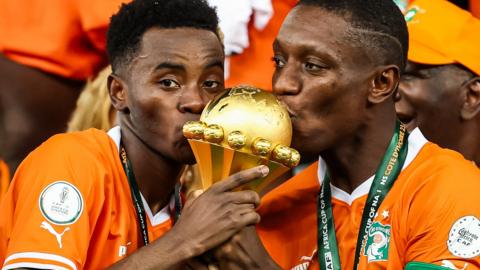 Simon Adingra and Max Gradel kiss the Africa Cup of Nations trophy