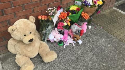 Floral tributes and teddies left outside the apartment block where Sanita Cawley was found injured