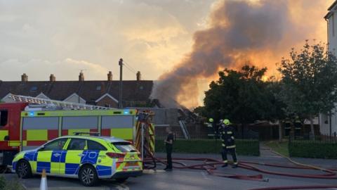 Fire crews tackling a blaze at a workshop with a big plume of smoke in the air