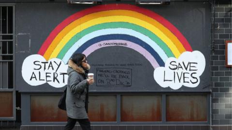 Woman walking past a rainbow mural