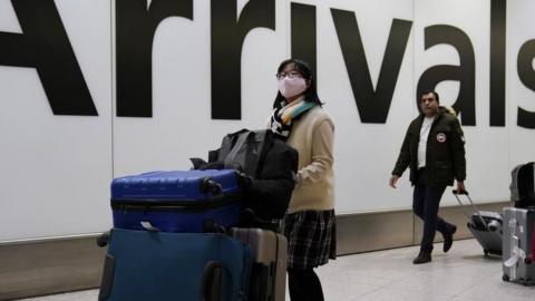 A passenger arrives wearing a mask at Terminal 4, Heathrow Airport, London