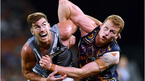 A Port Adelaide player and an Adelaide player grapple in a 2019 fixture