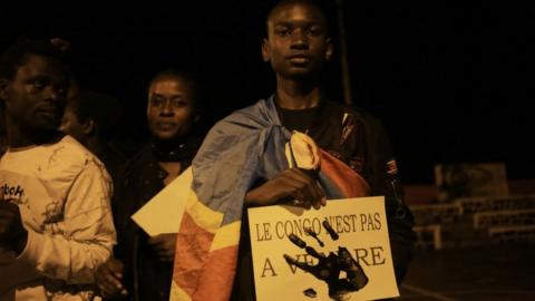 A young man holds a poster at a prayer vigil