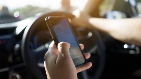 A man uses a mobile phone in his hand to navigate while driving