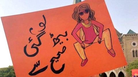 Rashida holding the "womanspreading placard"