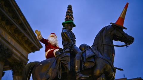 A man dressed in a Santa Claus suit scales the Duke of Wellington statue as Covid rules are tightened on December 21, 2021