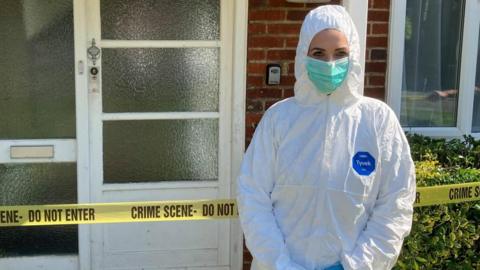 Picture of a house with crime scene tape across the door and a forensic officer in PPE