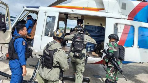 A handout photo made available by Papua Police Headquarters shows Indonesian police and military personnel boarding an helicopter during a search and rescue operation for Susi Air pilot and passangers at an airport in Timika, Papua, Indonesia 08 February 2023.