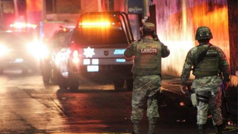 A soldier takes a picture with his phone at the scene where gunmen opened fire in two bars, killing at least 10 people, in Celaya, Mexico May 23, 2022.
