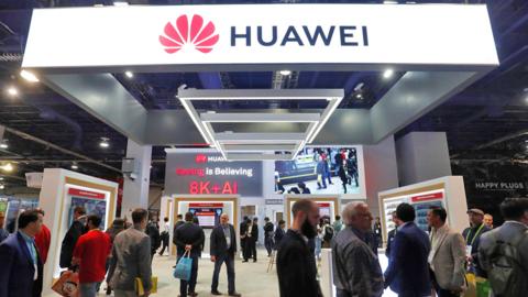 Attendees pass by a Huawei booth during the 2019 CES in Las Vegas