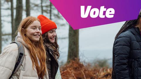photograph shows girls smiling and walking through woods on school trip with a vote icon in the top right corner of the image