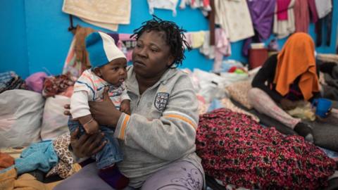 An illegal immigrant sits with a toddler at a detention centre in Zawiyah, west of the Libyan capital Tripoli