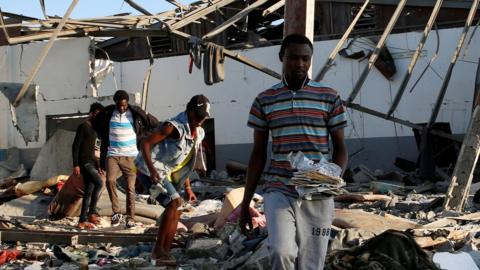 Migrants carry the remains of their belongings from among rubble at a detention centre for mainly African migrants that was hit by an airstrike in the Tajoura suburb of the Libyan capital of Tripoli, Libya July 3