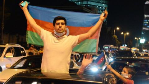 An Azeri protester holds the national flag in Baku amid pro-war demonstrations, after deadly border clashes with Armenia