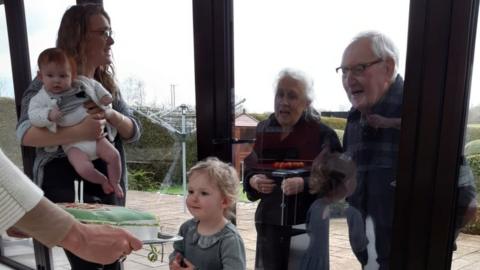 Lauren Godfrey with her grandparents looking through the glass