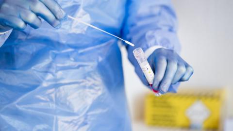 Close-up of a doctor putting a PCR test swab into a tube