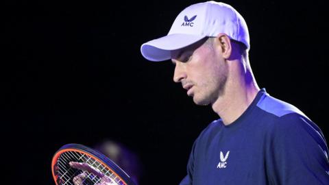 Andy Murray looks at the strings of his racquet