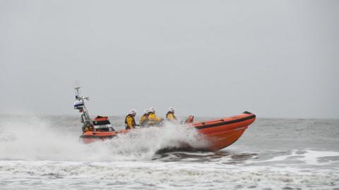 The lifeboat travelling across the water with fog beyond