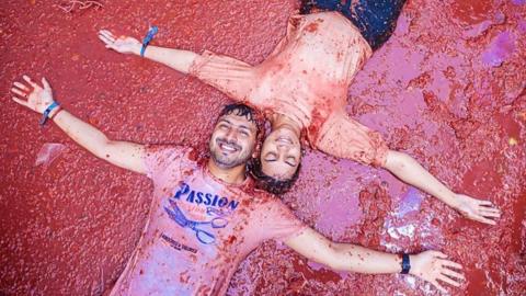 A man and woman lie in tomato juice on the floor