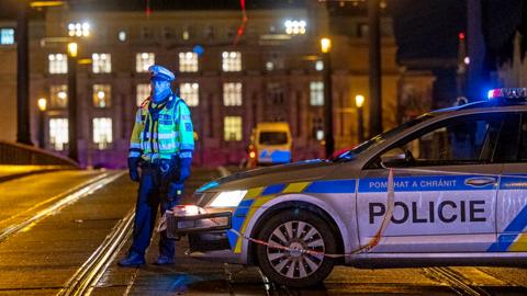 A police officer stands next to police car with building in background in Prague on 21 December