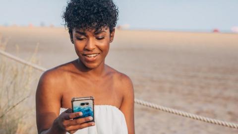 A woman on her phone on the beach